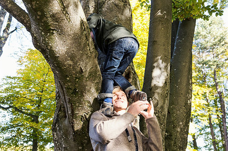 simsearch:649-05555429,k - Father helping son to climb tree, looking up smiling Stock Photo - Premium Royalty-Free, Code: 649-09209295