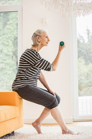 simsearch:693-05552857,k - Senior woman sitting on sofa exercising with dumbbell Stock Photo - Premium Royalty-Free, Code: 649-09209620