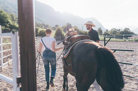 Young woman leading horse in rural equestrian arena Stock Photo - Premium Royalty-Free, Code: 649-09212948