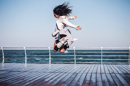 simsearch:649-08117852,k - Mid adult woman jumping mid air on sea pier, Odessa, Odeska Oblast, Ukraine Foto de stock - Sin royalties Premium, Código: 649-09213064