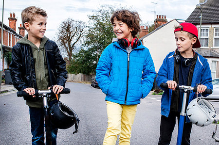 Boys riding push scooter on street Stock Photo - Premium Royalty-Free, Code: 649-09213490