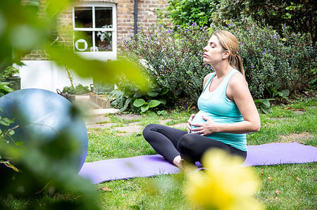 stomach (lower abdomen) - Pregnant mid adult woman practicing yoga meditation in garden Stock Photo - Premium Royalty-Free, Code: 649-09213675