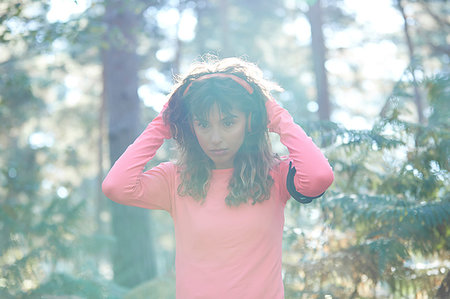 simsearch:693-07672615,k - Young female runner putting on headphones in sunlit forest Stock Photo - Premium Royalty-Free, Code: 649-09230218