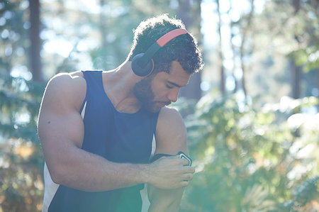 simsearch:693-07672615,k - Male runner using smartphone armband in sunlit forest Stock Photo - Premium Royalty-Free, Code: 649-09230221