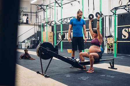 Trainer guiding pregnant woman using weights in gym Stock Photo - Premium Royalty-Free, Code: 649-09230596