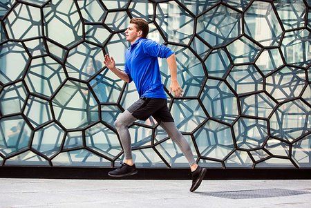 simsearch:614-08307669,k - Young runner jogging past glass wall, London, UK Stock Photo - Premium Royalty-Free, Code: 649-09246824