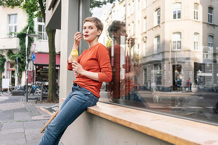 dreaming about eating - Woman eating ice cream in front of shop, Cologne, Nordrhein-Westfalen, Germany Stock Photo - Premium Royalty-Free, Code: 649-09249931