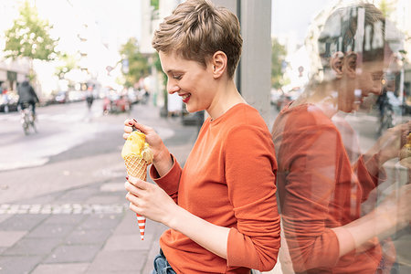 dreaming about eating - Woman eating ice cream in front of shop, Cologne, Nordrhein-Westfalen, Germany Stock Photo - Premium Royalty-Free, Code: 649-09249932