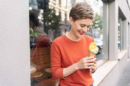 dreaming about eating - Woman eating ice cream in front of shop, Cologne, Nordrhein-Westfalen, Germany Stock Photo - Premium Royalty-Free, Code: 649-09249933