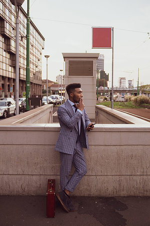 simsearch:614-06718128,k - Businessman using smartphone, smoking on pavement, Milano, Lombardia, Italy Stock Photo - Premium Royalty-Free, Code: 649-09257390