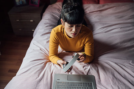 Woman using headphones with laptop on bed Stock Photo - Premium Royalty-Free, Code: 649-09257493