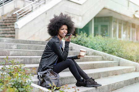 simsearch:614-09078761,k - Young woman with afro hair sitting on city stairway, talking to smartphone Stock Photo - Premium Royalty-Free, Code: 649-09257706