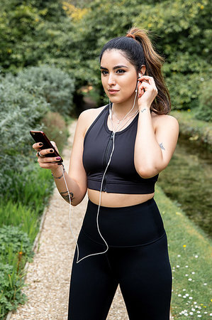 simsearch:693-07672615,k - Young female runner inserting earphones on riverside path Stock Photo - Premium Royalty-Free, Code: 649-09257725