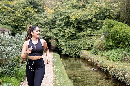 simsearch:693-07672615,k - Young female runner listening to earphones while running on riverside path Stock Photo - Premium Royalty-Free, Code: 649-09257727
