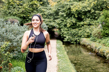 simsearch:693-07672615,k - Young female runner listening to earphones while running on riverside path Stock Photo - Premium Royalty-Free, Code: 649-09257728