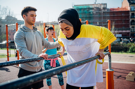 parallel bars - Calisthenics class at outdoor gym, male trainer encouraging young woman on parallel bars Stock Photo - Premium Royalty-Free, Code: 649-09257916