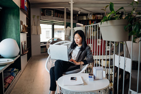 Young businesswoman using laptop in bookshop Stock Photo - Premium Royalty-Free, Code: 649-09258074