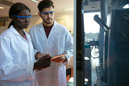 simsearch:649-08085222,k - Young female and male scientists looking at scientific equipment in laboratory Stock Photo - Premium Royalty-Free, Code: 649-09258381