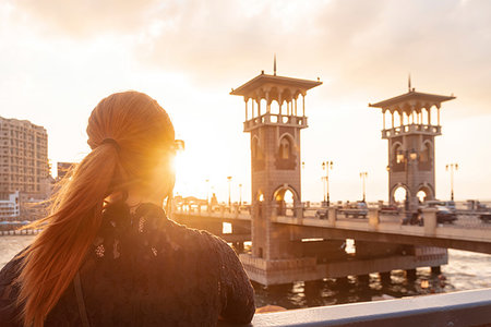 Female tourist with red hair looking out over Stanley bridge at sunset, rear view, Alexandria, Egypt Stock Photo - Premium Royalty-Free, Code: 649-09250315