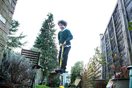 simsearch:649-07648247,k - Boy jumping on pogo stick in garden Stock Photo - Premium Royalty-Free, Code: 649-09250437