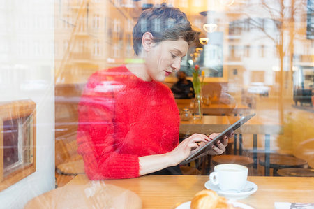 simsearch:649-07436838,k - Mid adult woman in cafe using digital tablet touchscreen, window view Stock Photo - Premium Royalty-Free, Code: 649-09251870