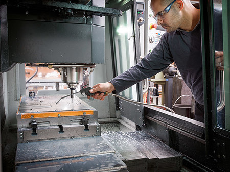 Knife factory worker spraying liquid onto machinery in workshop Foto de stock - Sin royalties Premium, Código: 649-09269003