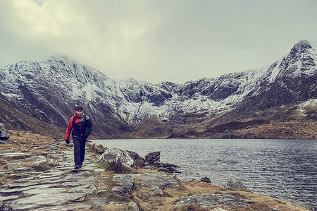 simsearch:649-08085723,k - Male hiker hiking alongside lake landscape with snow capped mountains, Llanberis, Gwynedd, Wales Foto de stock - Sin royalties Premium, Código: 649-09269118