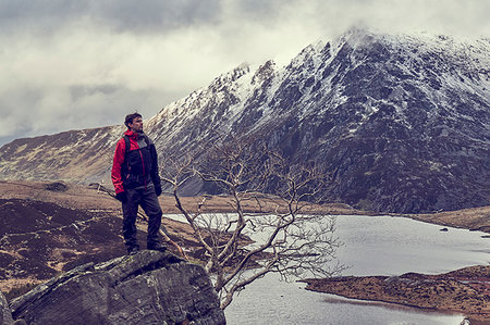 simsearch:649-08085723,k - Male hiker looking out at lake and snow capped mountain landscape, Llanberis, Gwynedd, Wales Foto de stock - Sin royalties Premium, Código: 649-09269127