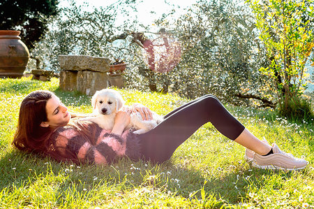 simsearch:649-06401393,k - Girl lying in orchard with a cute golden retriever puppy on her stomach, Scandicci, Tuscany, Italy Stock Photo - Premium Royalty-Free, Code: 649-09269137