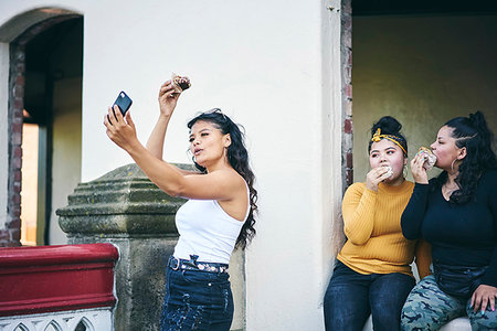 simsearch:649-07736862,k - Young woman taking selfie with teenage sisters while eating cakes in doorway Stock Photo - Premium Royalty-Free, Code: 649-09275609