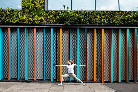 simsearch:6118-07731916,k - Young woman practicing yoga pose on city sidewalk, arms and legs outstretched Photographie de stock - Premium Libres de Droits, Code: 649-09275976