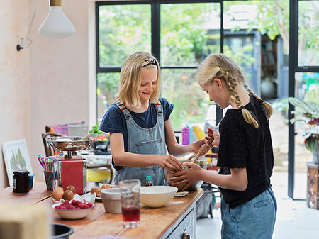 simsearch:614-06897440,k - Girl and her sister baking a cake, stirring cake mixture in mixing bowl at kitchen table Stock Photo - Premium Royalty-Free, Code: 649-09276196