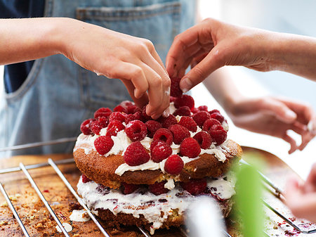 simsearch:614-06897440,k - Girl and her sister baking a cake, decorating cake with fresh cream and raspberries at kitchen table, cropped view of hands Stock Photo - Premium Royalty-Free, Code: 649-09276209