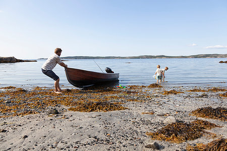 simsearch:649-08004031,k - Father pulling boat onto beach, sons playing nearby, Norway Stock Photo - Premium Royalty-Free, Code: 649-09277589