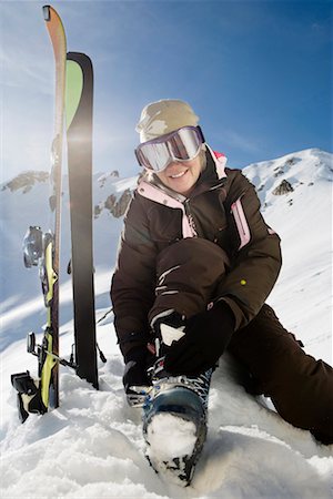 Mature female skier fastening boot bindings on mountain Stock Photo - Premium Royalty-Free, Code: 649-01556036