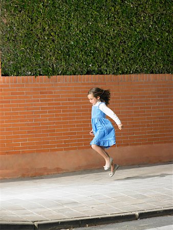 Little girl skipping down pavement, Alicante, Spain, Stock Photo - Premium Royalty-Free, Code: 649-01556957