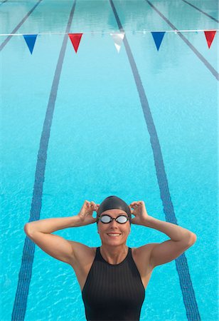 Female swimmer adjusting goggles by pool, smiling Stock Photo - Premium Royalty-Free, Code: 649-01557752