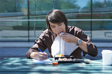 Businessman eating sushi and doing work while outside. Stock Photo - Premium Royalty-Free, Code: 649-01609857
