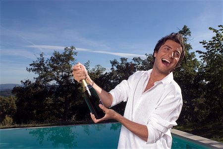 pool party - Man opening a bottle of champagne by a pool Stock Photo - Premium Royalty-Free, Code: 649-01610164
