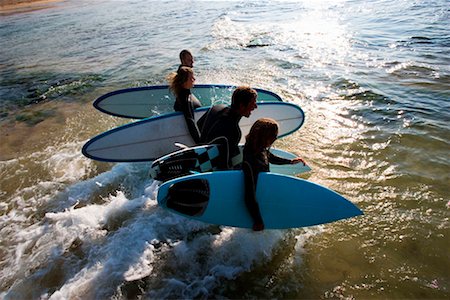 simsearch:649-01696512,k - Four people carrying surfboards into the water laughing. Stock Photo - Premium Royalty-Free, Code: 649-01696056