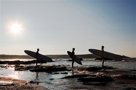 simsearch:649-01696512,k - Three people holding surfboards standing on large rocks. Stock Photo - Premium Royalty-Free, Code: 649-01696093