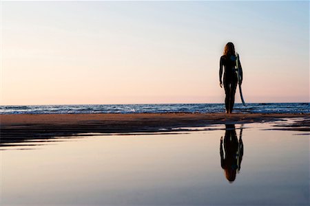 silhouettes surfboards in the sand - Woman standing on the beach holding surfboard. Stock Photo - Premium Royalty-Free, Code: 649-01696111