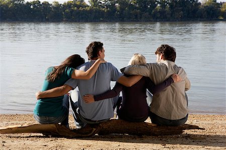 simsearch:649-01696405,k - Four friends sitting on log by a lake with arms around each other. Stock Photo - Premium Royalty-Free, Code: 649-01696247