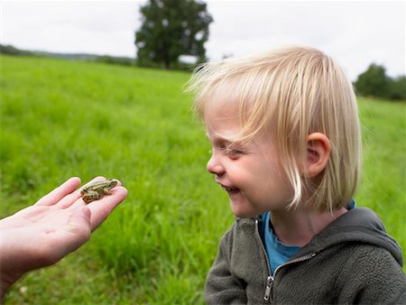 Young girl smiling looking at a small frog held in a man's hand. Stock Photo - Premium Royalty-Free, Code: 649-01696494