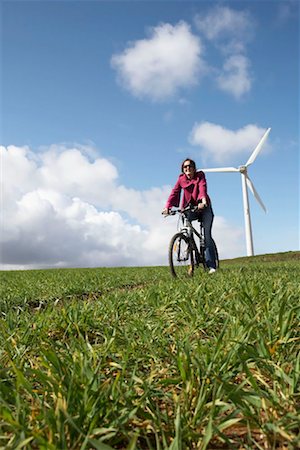 Woman riding a bike on a wind farm Stock Photo - Premium Royalty-Free, Code: 649-02199583