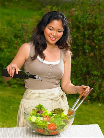 Young woman pouring olive oil on salad Stock Photo - Premium Royalty-Free, Code: 649-02290555