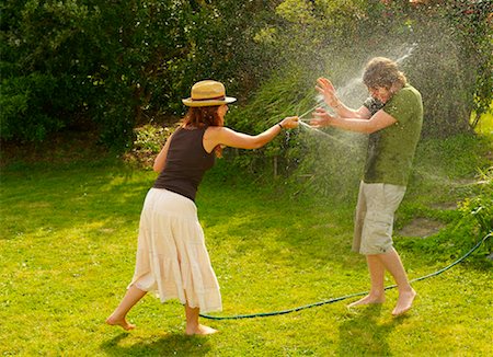 Woman spraying man with garden hose Stock Photo - Premium Royalty-Free, Code: 649-02290560