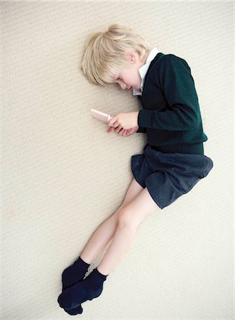 school boys side - Boy lying on floor playing with nintendo Stock Photo - Premium Royalty-Free, Code: 649-02424081