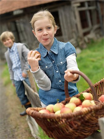 Girl with apple basket eating apples Stock Photo - Premium Royalty-Free, Code: 649-03008671