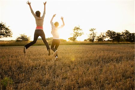 running in the fall - Deux jeunes filles sautant dans un champ de maïs Photographie de stock - Premium Libres de Droits, Code: 649-03297702